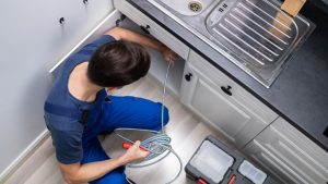 Plumber Cleaning Clogged Sink Pipe