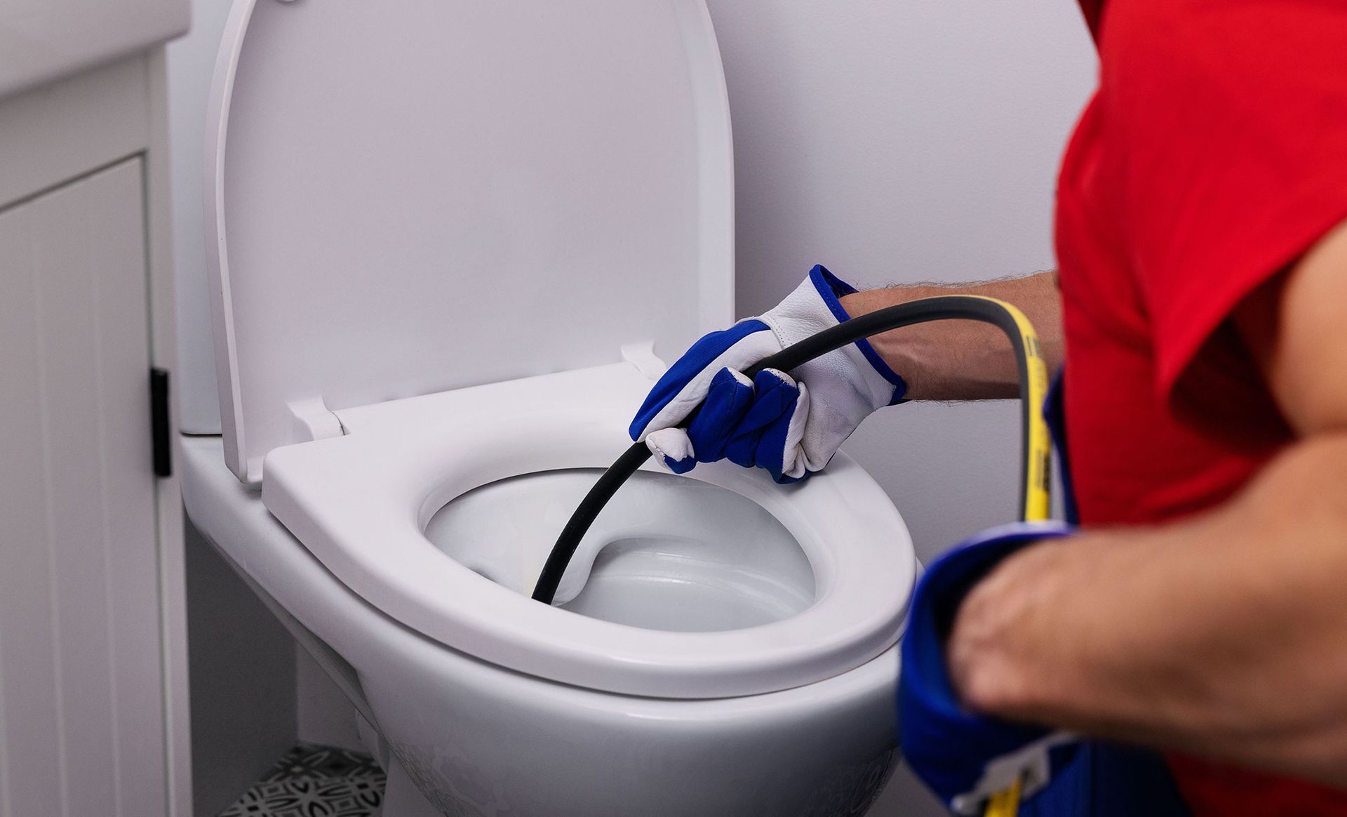 Plumber cleaning a toilet drain
